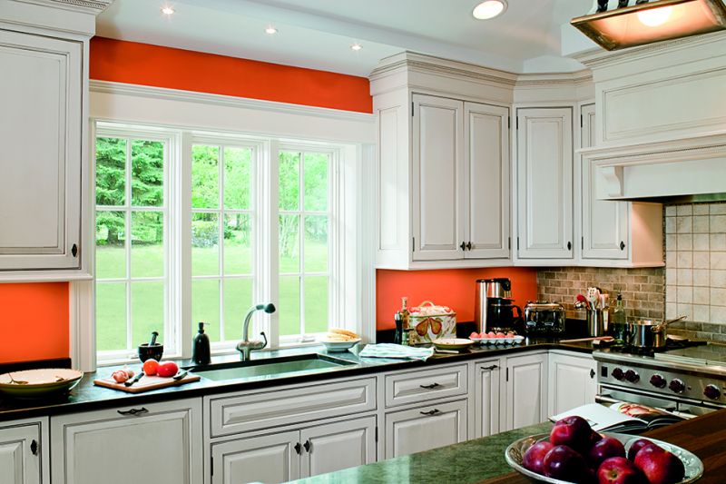 a kitchen with white cabinets and orange walls