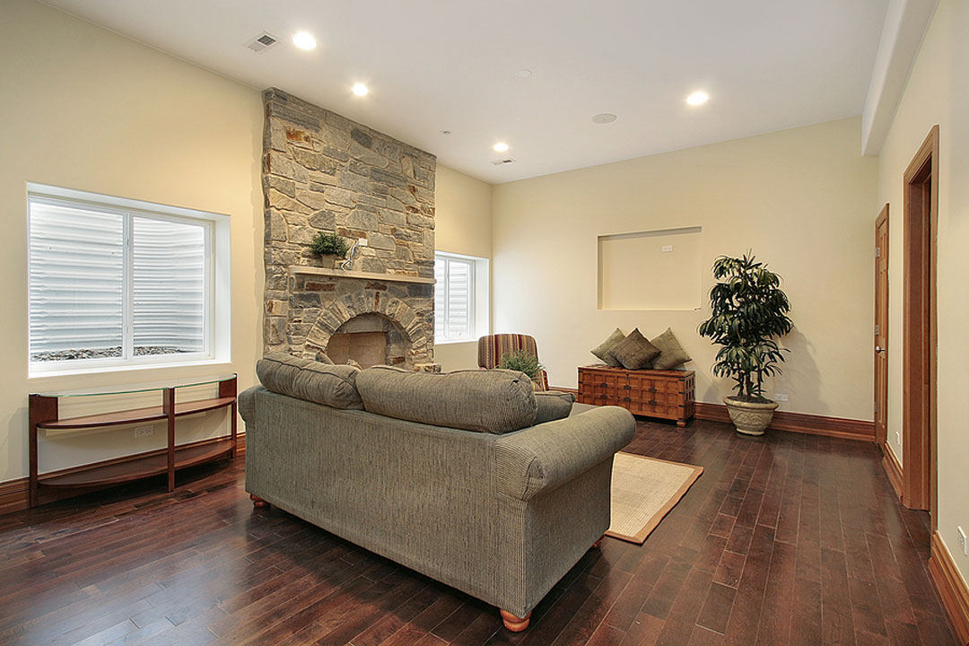 a living room with a stone fireplace and wood floors