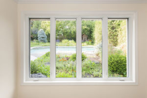 Four casement windows in a row in a white frame with a view of a green yard.