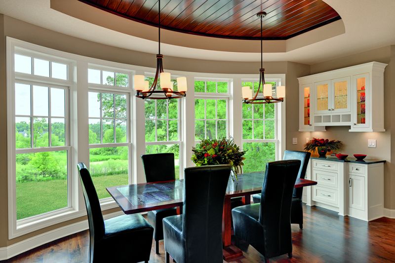 a dining room table with black chairs and windows