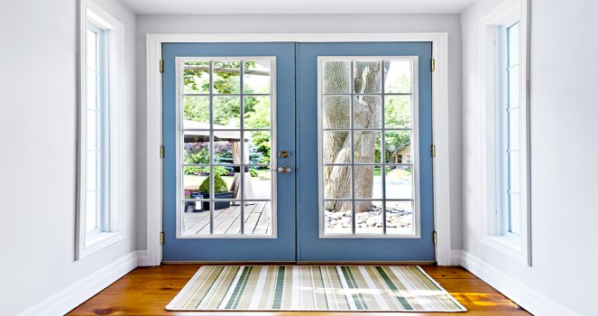 a blue front door with two windows and a rug on the floor