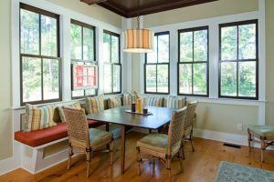 A kitchen with a breakfast nook surrounded by large double-hung windows