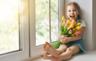 Young girl sitting by window hugging a bundle of tulips
