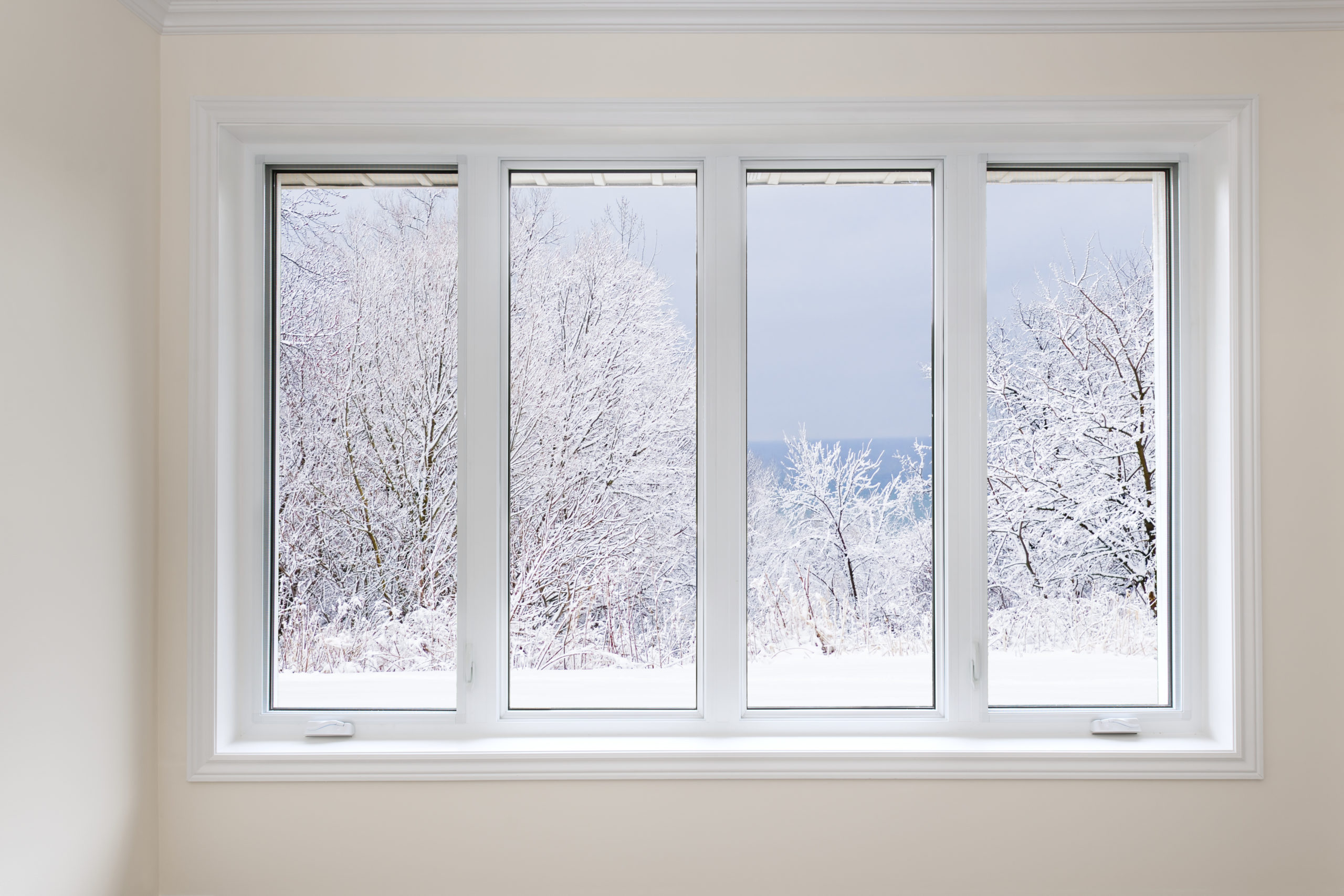 Large window with four panes looking out onto snow covered trees