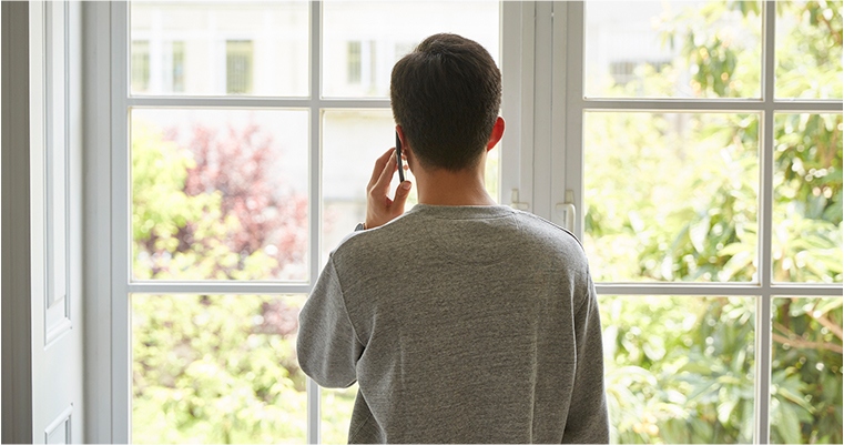 man looking out the window talking on the phone