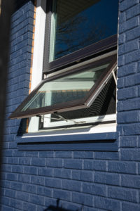 Exterior view of open awning window in blue brick home.